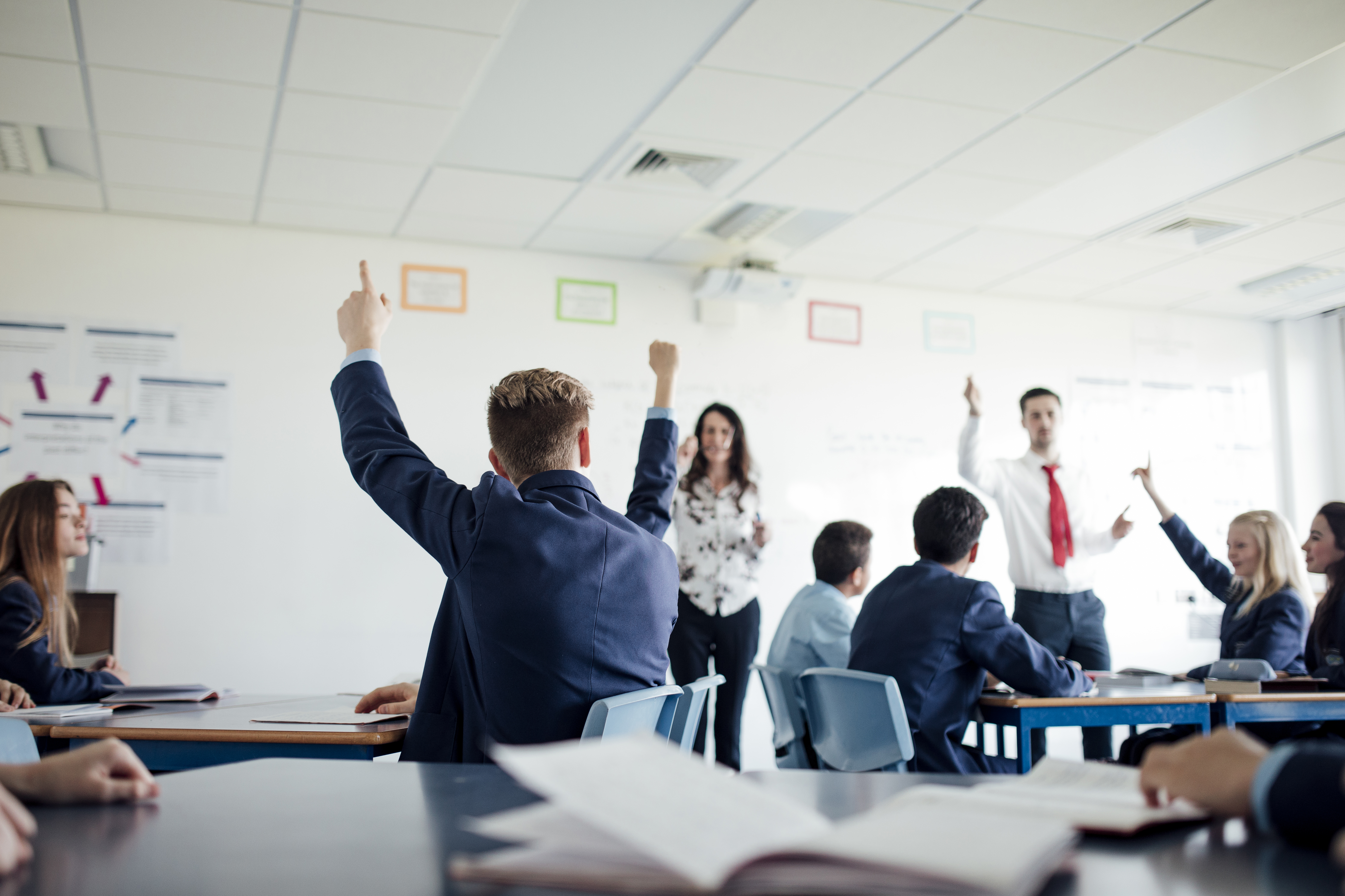 Students raising their hands in a classroom